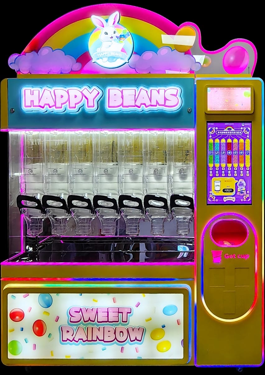 Happy Beans candy vending machine with illuminated rainbow sign, multiple sweet dispensers across the front, a tall digital touchscreen panel and Sweet Rainbow lower panel.
